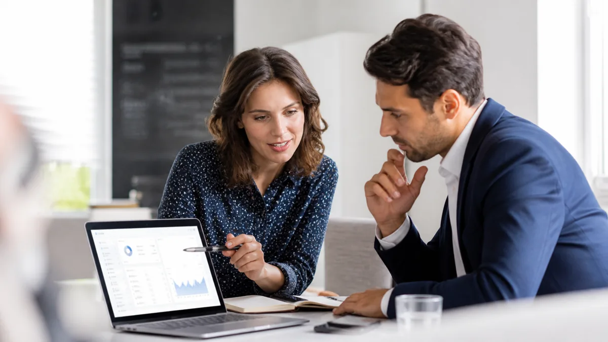 Photorealistic image of two professionals reviewing a software product demo together on a laptop.